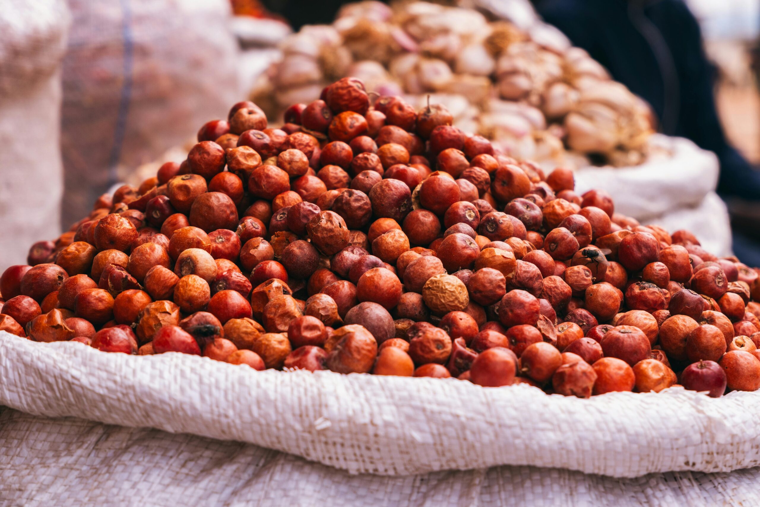 Close-up of locust bean pods stacked in sacks at a market in Jos, Nigeria.
