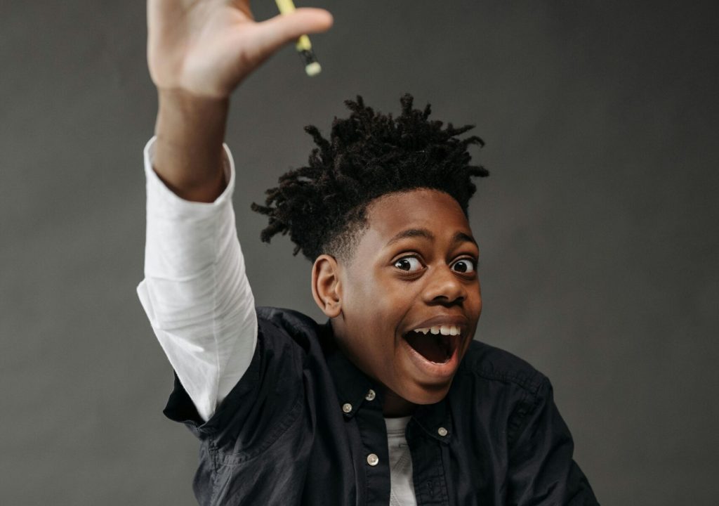 An excited student raises his hand during a classroom activity, showcasing eagerness to participate.